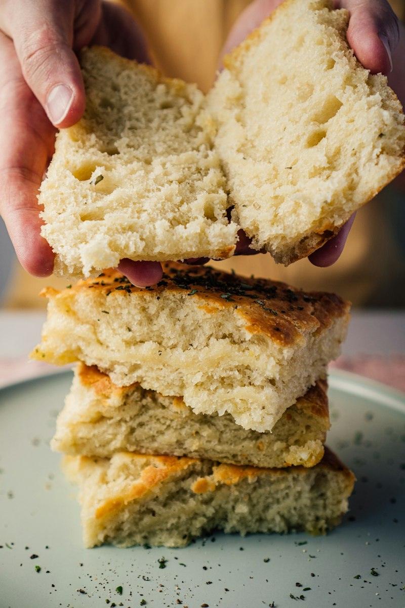 Mani che aprono una focaccia alta e morbida