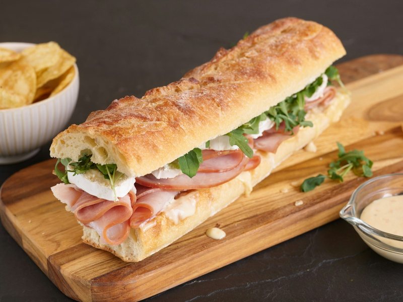 Focaccia farcita con prosciutto, mozzarella e rucola sul tagliere