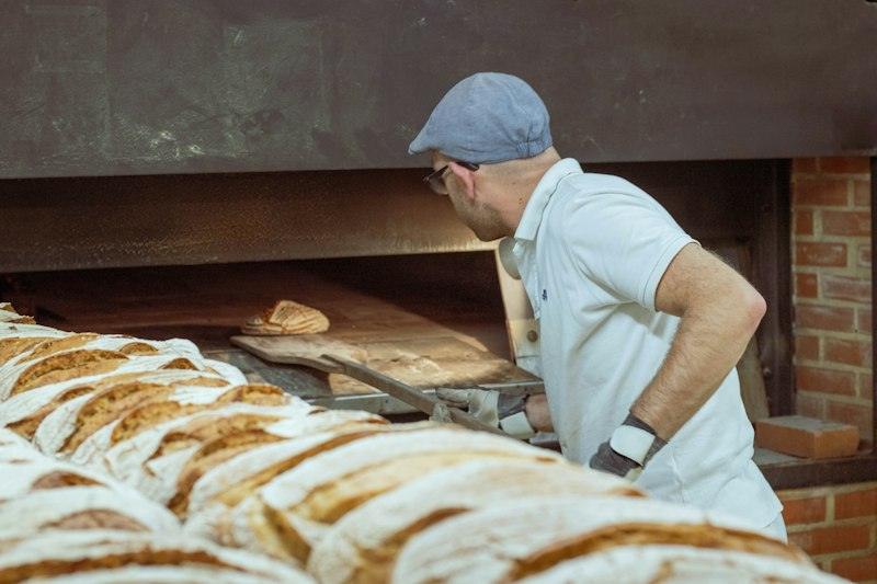 Un fornaio che sforna il pane dal forno a legna