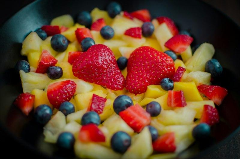 Macedonia di fragole, mirtilli e ananas in una ciotola scura