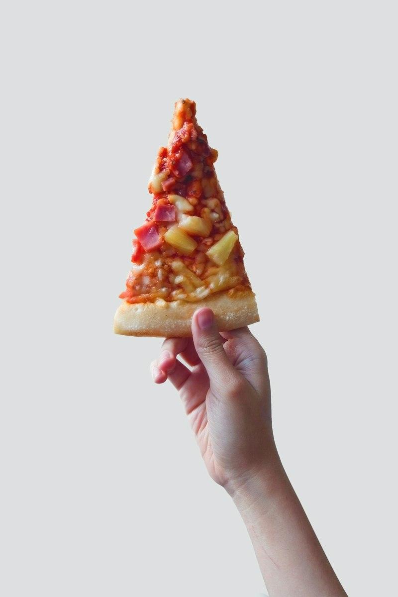 Una mano che tiene un trancio di pizza
